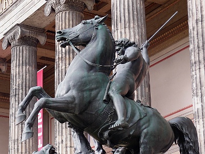 Lion fighter  Löwenkämpfer is a bronze sculpture by the German sculptor Albert Wolff after a design by Christian Daniel Rauch . Shown is a rider on a rearing horse who is about to pierce a lion lying on the ground with his lance . The sculpture was made by the foundry Hermann Gladenbeck and set up in 1861 on the western stair cheek of leading to the pleasure garden outside staircase of the Old Museum in Berlin