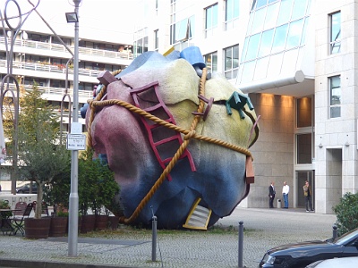 Houseball  'Houseball', 1996, was designed by the artist Claes Oldenburg and his wife, writer Coosje van Bruggen. It is currently located at Bethlehemskirchplatz on Mauerstrasse, downtown Berlin. The sculpture, 27 ft. 6 in. or 8.4 m. high with a diameter of 24ft. 4 in. or 7.4 m., symbolizes the meager household goods a refugee carries on his or her back.