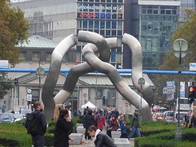 "dancing spaghetti  Artwork made of stainless steel for the 750 anniversary of Berlin The four arms symbolize the four sectors in which Berlin was divided after the war.  "The possible, but actually not executed connection of the elements depicts a paradox of split and togetherness. " [Mirjam Brusius] "The sculpture is to be committed from all sides, to go in every direction and thus physically experienceable. The passage direction west-east and east-west is emphasized.