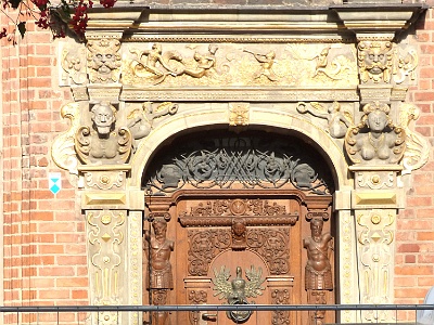 Doorway of New Bench House  The New Bench House is also called the Gdańsk Entrance Hall. In 1712-1806 it was occupied by the magistrate court (lay judges). Between 1901 and 1945 its authentic hall served as an art gallery.At one p.m. every afternoon (and at three and five p.m. in the season) a sweet girl's face appears in one of the windows of the New Bench Hall. This is Hedwiga, a legendary 17th century maiden said to have been kept prisoner there by her uncle. In 1891 the girl, heroine of an old romance, became the protagonist of its novelised version entitled 'The Maiden in the Window' by Jadwiga Łuszczewska (Deotyma). Generation after generation indulged in the book and upon arriving in Gdańsk would look for the house and the pretty lass lurking in the window.