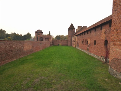 Malbork Castle  The castle was expanded several times to house the growing number of Knights. Soon, it became the largest fortified Gothic building in Europe,[6] on a nearly 21-hectare (52-acre) site. The castle has several subdivisions and numerous layers of defensive walls. It consists of three separate castles - the High, Middle and Lower Castles, separated by multiple dry moats and towers. The castle once housed approximately 3,000 "brothers in arms". The outermost castle walls enclose 21 ha (52 acres), four times the enclosed area of Windsor Castle