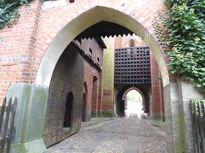 Malbork Castle  During the Thirty Years' War, in 1626 and 1629 Swedish forces occupied the castle. They invaded and occupied it again 1656 to 1660 during the Deluge.  The main entrance provides access to the Middle Castle. It is secured with five iron-bound gates standing one behind the other. Behind the first massive arch lies a wooden bridge that spans over a moat. Today it is static, but in the past it could be drawn up. Past this lies a portcullis, which could be lowered almost instantaneously if the castle was under threat. The ground is corbelled, and specially-laid stones marked the way for carts to they did not damage the walls. Malbork’s gates were designed to accommodate horses, but each was equipped with a smaller door that could be opened to admit those travelling by foot.