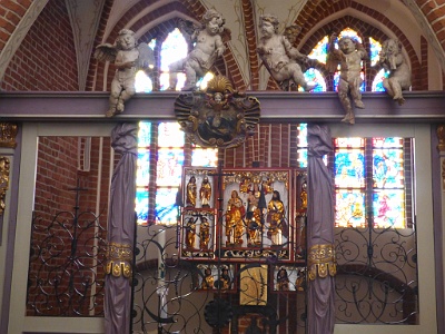 Baptismal Chapel  The altar ( triptych ) was made in the 1920s in the workshop of Claus Berg in Lübeck . In the center of the composition is Our Lady with Baby. There are two angels holding the crown. Mary stands for the sorrow of the moon, symbolizing the victory over the forces of evil and Satan. Next to St. Magdalena and the unidentified saint . On the wings of the triptych there are sculptures of 8 saints , and below (in predella ) contemporary representations of the four evangelists . Below the altar is a reliquary mounted with relics of St. Otto , donated in 1974 by Bishop Bamberg . In the chapel there is also an antique, 17th-century baptismal font from Dobropola - a work by artists Christophe Schmidt - carpenter and painter Joachim Sellin. The font was made in Wolin . The chapel from the nave separates the decorative, baroque wooden partition from the church in Stolc.