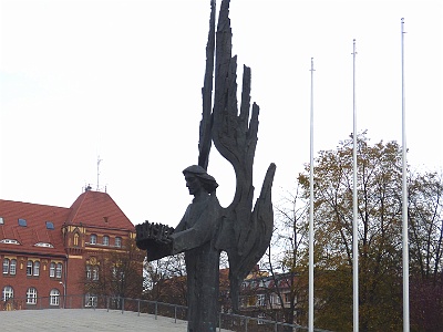 Monument to the Victims of December 1970  Protests of workers in Poland on 14-22 December 1970 ( demonstrations , protests, strikes , riots , riots ) mainly in Gdynia , Gdansk , Szczecin and Elblag , suppressed by militia and army The bronze sculpture , designed by Czeslaw Dźwigaja , is 11 meters high and weighs 9.5 tons [1] . It depicts an angel with vertically raised wings, holding a crown of thorns in his hands, styled in the stylized inscription December 1970. The angel stands on a boat that emerges from the ground, shattering the surrounding pavement . Around the statue are four vertical granite slabs with souvenir inscriptions and names of the fallen in December 1970.