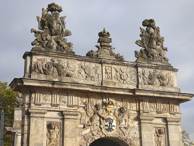 Backside of the Royal Gate  Particularly noteworthy are the sculptures by Frederick William I , Bartholome Damarath, the sculptor of the Prussian King. Mars with sword and shield and Hercules with mace and leopard skin, and placed over the passage of the panoply of the Prussian Eagle, surrounded by the chain of the Black Eagle and crowned with a royal crown. The gate is adorned with carved elements of armor, armor, shields and banners - it is a reference to the Roman tradition of triumphal triumphs and the hanging of weapons at the gates of cities.